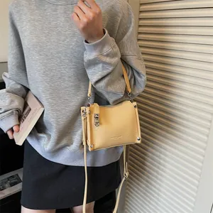 Close-up of creamy yellow crossbody bag with lychee texture and metallic hardware