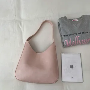 Borsa hobo rosa minimalista stesa accanto a un tablet che ne mostra capacità e dimensioni