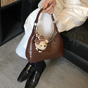 Sac hobo marron à motif crocodile avec pendentif ours en peluche porté par un mannequin