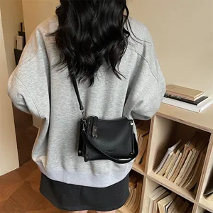 Detail of classic black lychee leather crossbody bag on a model in a library setting