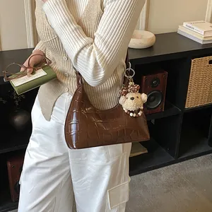 Détail du sac à bandoulière marron foncé motif crocodile avec breloque ours et perles