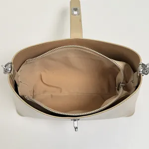 Top view of beige bucket bag interior with zipper compartment and silver metal hardware