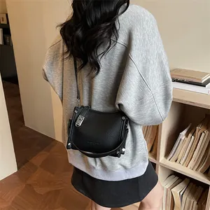 Detail of black pebbled leather crossbody bag with silver hardware on model back view