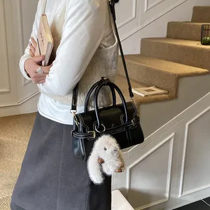 Detail of vintage black handbag featuring white stitching and a cute rabbit charm accessory