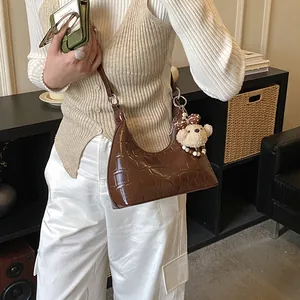 Sac bandoulière marron motif crocodile avec charm ours en peluche sur un modèle