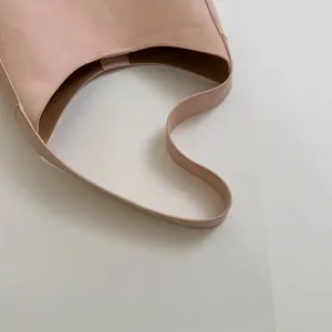 Dettaglio dell'apertura curva e della trama in pelle liscia di una borsa hobo rosa nude