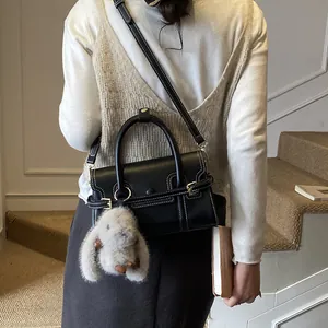 Detail of vintage black leather bag with contrast stitching and plush rabbit charm