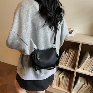 Close-up of black pebble leather crossbody bag featuring silver zippers and hardware