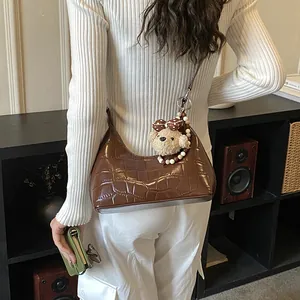 Gros plan du sac hobo marron foncé à texture croco avec charm ours et porte-carte vert