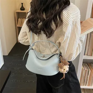 Détail du sac à main en cuir bleu clair avec breloque d'ours en peluche mignon