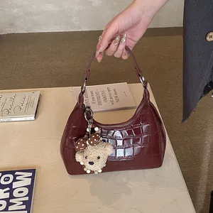 Détail d'un sac hobo bordeaux effet crocodile avec un pendentif ours à nœud