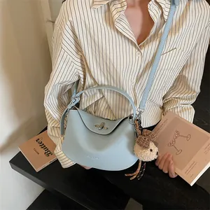 Détail du sac à main en cuir bleu clair avec fermoir rotatif et breloque ours en peluche