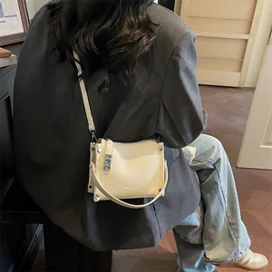 Detail of creamy white pebble leather crossbody bag with silver hardware and engraving