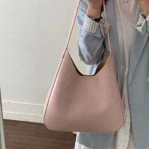 Borsa hobo minimalista in pelle rosa chiaro abbinata a blazer blu e abito bianco