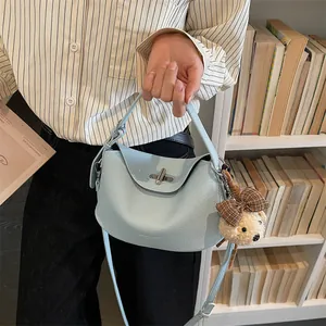 Détail d'un sac bleu clair en cuir grainé avec fermoir argenté et pendentif ours