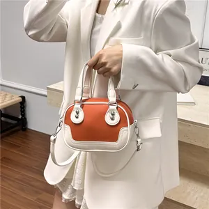 Detail der orangefarbenen Boston Bag mit Paspeln, Nieten und abnehmbarem Gurt am Modell