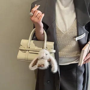Chic beige handbag detail with a fluffy rabbit plush charm for a stylish commute