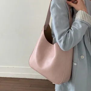 Dettaglio della borsa tote in pelle rosa chiaro abbinata a un blazer blu stile casual