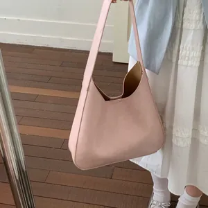 Vista dettagliata della borsa tote minimalista in pelle rosa indossata a spalla da modella