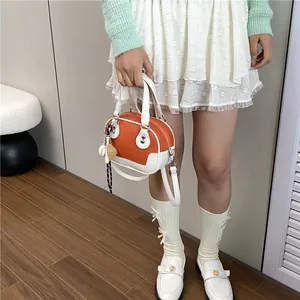 Detailansicht der orange-cremefarbenen Boston-Tasche, kombiniert mit einem Outfit