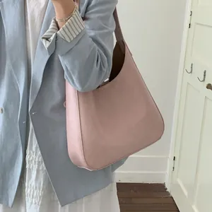 Dettaglio di una grande borsa tote rosa con texture in pelle opaca e design minimalista