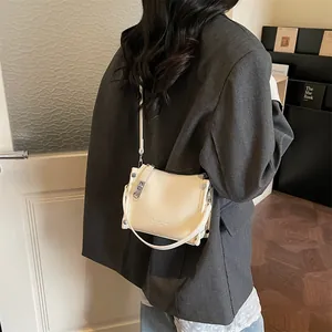 Close-up of cream square bag showing lychee grain leather texture and metal buckles