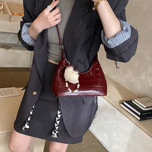 Détail du sac hobo bordeaux à texture crocodile et joli pendentif en mouton peluche