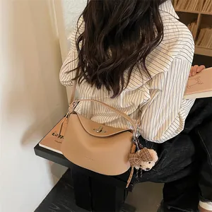 Détail d'un sac bandoulière beige grainé avec fermoir métal et charm ourson