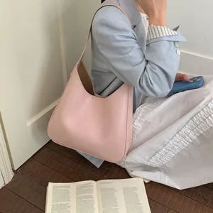 Dettaglio dell'elegante borsa tote in pelle rosa con cuciture rifinite su una modella