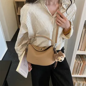 Détail du sac à main en cuir beige avec pendentif ours et fermoir métallique chic