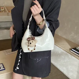 Détail du sac hobo blanc à motif crocodile avec un adorable porte-clé ours en peluche