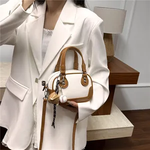 Detail einer Mini-Bowlingtasche in Beige und Braun, gehalten von Modell im Anzug
