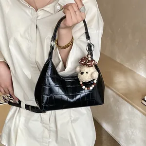 Détail du sac à bandoulière noir en similicuir avec texture croco et charm ours en peluche