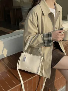 Chic beige lychee leather crossbody bag with silver buckle in a street style setting