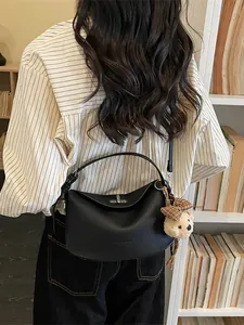 Sac Boston minimaliste en cuir grainé noir avec fermoir en métal et breloque ours