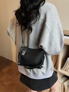 Vintage black lychee leather crossbody bag with silver hardware on a female model