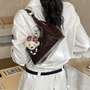 Détail du sac hobo en similicuir crocodile marron avec un pendentif en forme d'ours