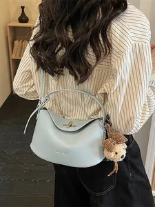 Sac à main en cuir bleu clair grainé avec charm d'ours et fermoir rotatif argenté