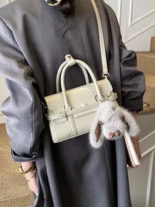 Retro cream crossbody bag with leather strap and gray plush rabbit pendant on shoulder