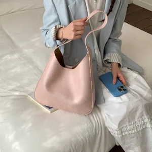 Dettaglio della borsa tote in pelle opaca rosa tenue indossata con un blazer blu
