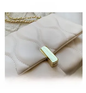 Detailed view of beige crossbody bag featuring wave quilted leather and gold buckle