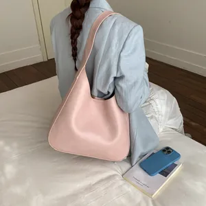 Dettaglio della borsa tote in pelle PU opaca rosa indossata da una modella in stile minimal