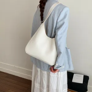 Vista modella di una grande borsa hobo bianca con ampia tracolla dal design minimalista
