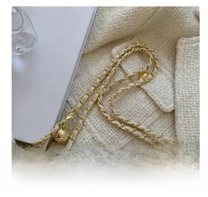 Close-up of golden metal chain strap with leather interweaving and ball adjuster detail