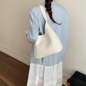 Dettaglio della borsa a spalla a mezzaluna bianco sporco in pelle minimalista