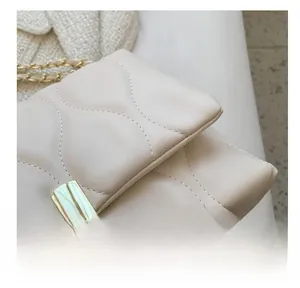 Close-up of diamond-patterned stitching and golden square buckle on the off-white bag
