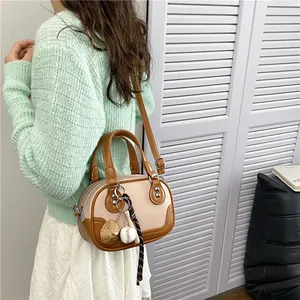 Detail der zweifarbigen Bowlingtasche in Beige und Braun mit einem Baseball-Themenanhänger