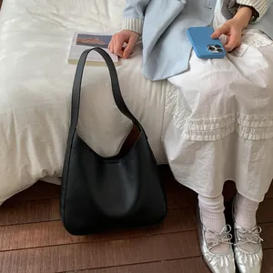 Dettaglio della borsa tote nera in pelle martellata abbinata a un outfit chic da ufficio