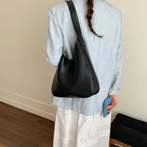 Borsa hobo minimalista in pelle nera opaca su modella con dettaglio della tracolla larga