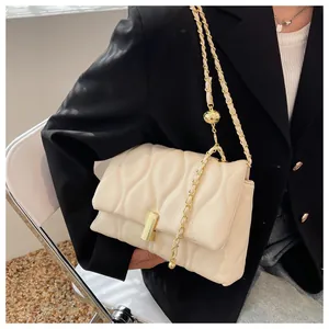 Detail of a creamy white chain bag with wave quilted pattern and golden buckle